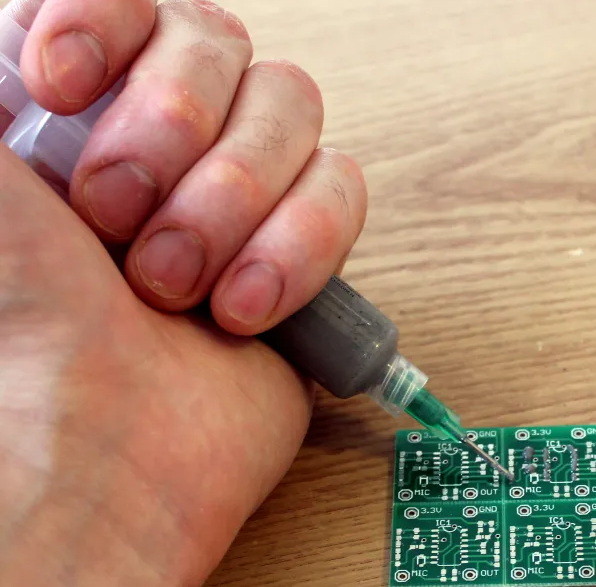 工程师使用注射器分配器涂抹焊膏。